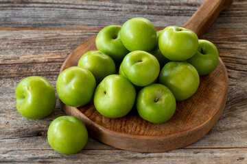 fresh green plums on wood background. Close up