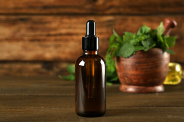 Naklejka premium Glass bottle of nettle oil with dropper on wooden table
