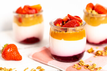 Fruit yogurt berry with muesli and fresh strawberries, on a white wooden background