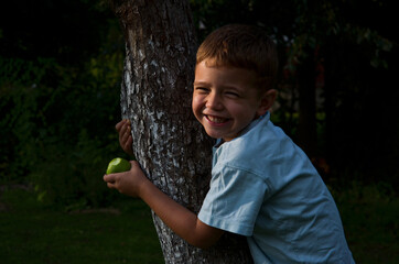 happy child eating apple on tree