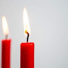 Burning red candle on a white background.