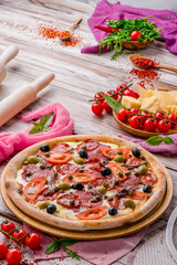 Juicy pizza with sausages, tomatoes and olives on a white wooden background. Space for text. High quality photo