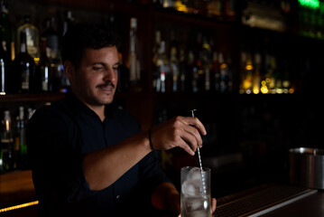 bartender stirring ice with utensil in the glass
