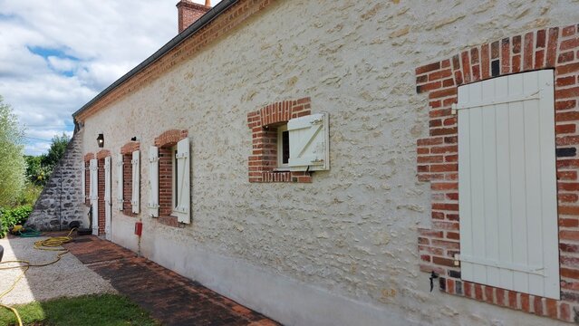 Maison avec fa&ccedil;ade en pierre de calcaire type moellon et volets blancs