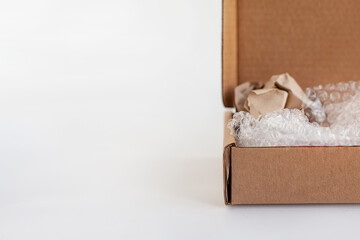 Cropped image of a cardboard box with wrapping paper and bubble wrap inside. Product packaging...