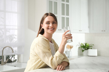 Woman with glass of tap water in kitchen
