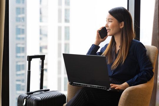 Asian Businesswoman Using Laptop Working In Hotel Room Remotely On Her Business Travel