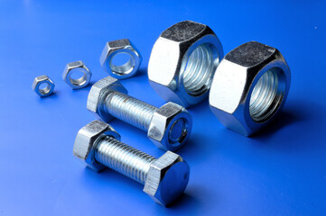 chrome-plated, metal nuts of different sizes are laid out on a blue background.