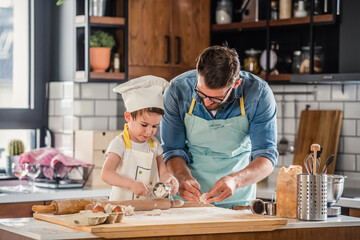 Family together in the kitchen. Father making cake with his toddler son.