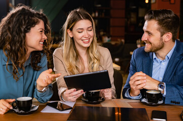 Young businesspeople having work meeting in the restaurant, drinking coffee, discussing business