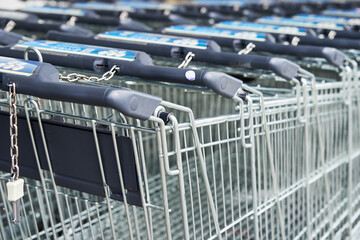 Many empty shopping carts on the shop parking. Row of shopping trolleys for supermarket buyers