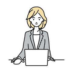 デスクで座ってPCを使っているスーツの女性