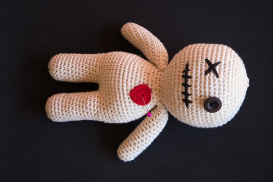 voodoo doll lying on a black background.