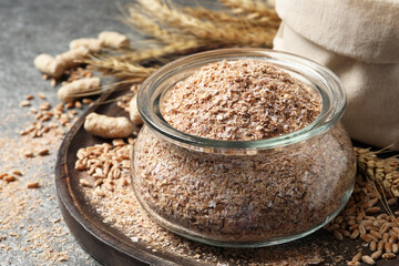 Jar of wheat bran on grey table