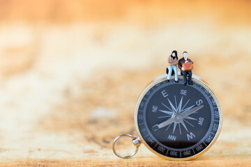 Miniature people Group of young tourist traveler traveling sitting on Golden Compass as travel...