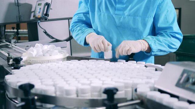Pharmacologist is displacing pill tubs from the conveyor