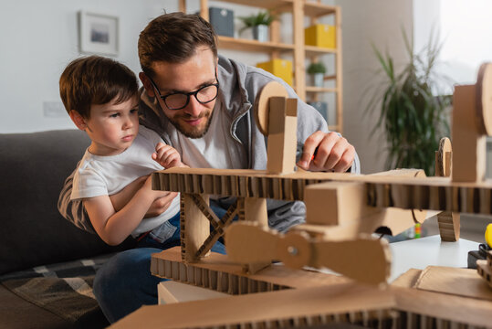 Father making cardboard airplane for his toddler son