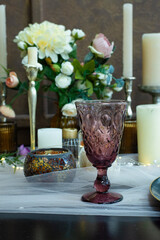 table served with burgundy glasses, flowers, candles and a garland. A glass with a plate. Candles on the table. Romantic table setting.