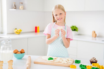 Obraz na płótnie Canvas Photo of young happy joyful small girl hold hand cookie heart shape baker smile indoors inside house kitchen