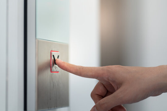 Action of human is pressing on button switch for call the elevator. Close-up and selective focus at the human's finger.