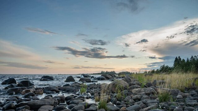 4K time lapse of Magnificent Soft and colorful sunset by the seaside stone. Beautiful cloud movement with seashore stones. Gradual light reduction.