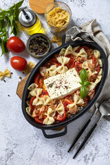 Baked feta pasta, or Tiktok pasta on gray background. Oven baked feta pasta made of tomatoes, feta cheese, garlic and herbs. Top view flat lay background. Copy space.
