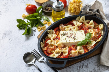 Baked feta pasta, or Tiktok pasta on gray background. Oven baked feta pasta made of tomatoes, feta...