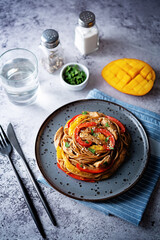 Buckwheat pasta with chicken, mango and red pepper in a plate