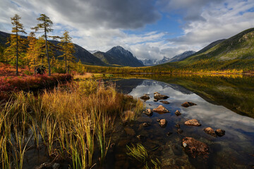 Photographer in the open air on an autumn sunny day on the shore of a mountain lake