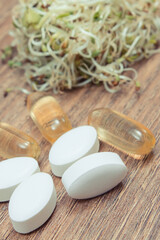 Radish sprouts containing vitamins and tablets supplements. Choice between healthy eating and pills