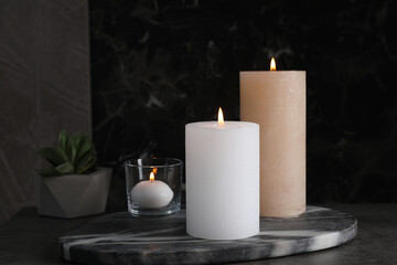 Obraz na płótnie Canvas Marble board with burning candles on dark table