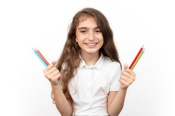 education, creativity, people, kids and school concept. Little student girl showing colorful crayons on white background.