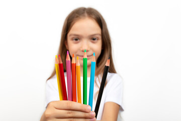 education, creativity, people, kids and school concept. Little student girl showing colorful crayons on white background.