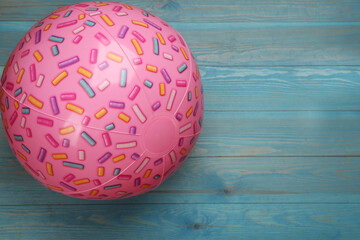 Pink beach ball on light blue wooden background, top view. Space for text