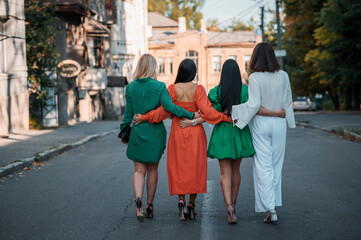 Fototapeta na wymiar Street Fashion. Four beautiful fashionable girlfriends walk in sunny weather in the city. 