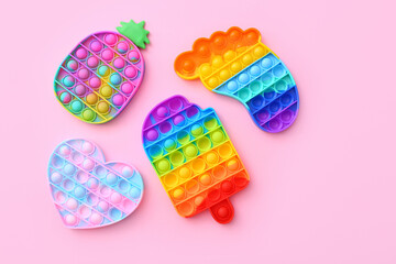 Colorful Push Pop It Bubble Sensory Fidget Toys of different shapes on pink background, top view