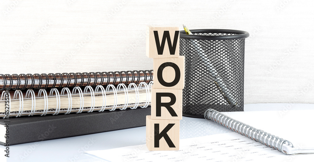 Poster work text on wooden block with notebooks on white background