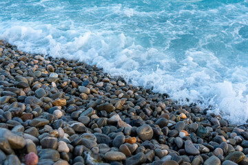 Blue sea water is washed on the stony pebble beach, concept of vacation and freedom 