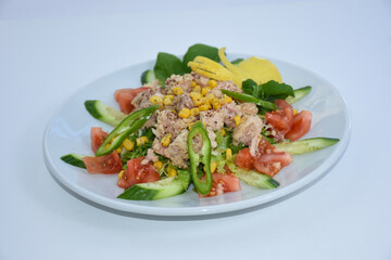  tuna fish salad with tomatoes, arugula, corn served on white plate