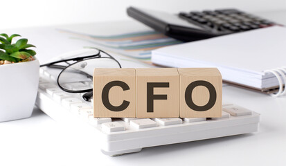 CFO written on a wooden cube on keyboard with office tools