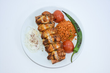Close up of Chicken wings served on a plate with bulgur pilaf, roasted tomatoes and peppers