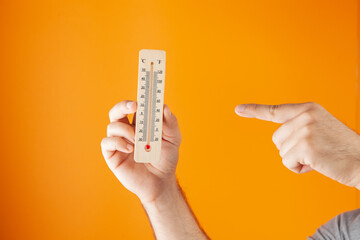 hand holds a home thermometer. air temperature