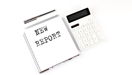 Notepad with text NEW REPORT with calculator and pen. White background. Business concept