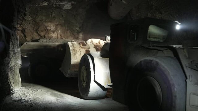 After the ore is loaded, the underground dump truck and loader drive off down the mine