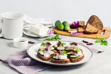 Canapes with toasted bread with sunflower and flax seeds, feta cheese, cucumber and onion