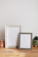 Empty photo frames and succulent on wooden table indoors