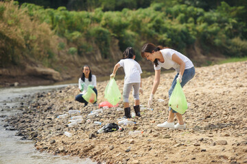 Group of volunteer people collecting trash near river. Ecology charity and clean environment concept
