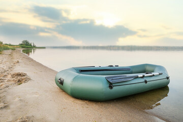 Inflatable rubber fishing boat on sandy beach near river
