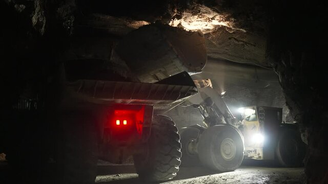 Underground loader loads ore mass into an underground dump truck