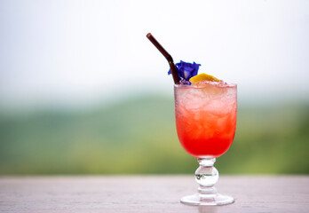 Italian red cold soda on wooden table in natural atmosphere against blurred background..